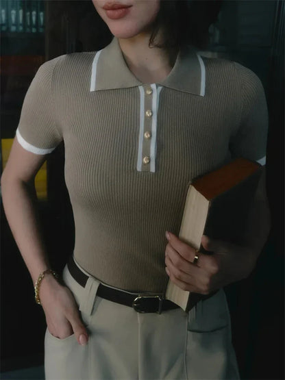 Woman wearing white ribbed knit polo shirt with brown belt and beige trousers