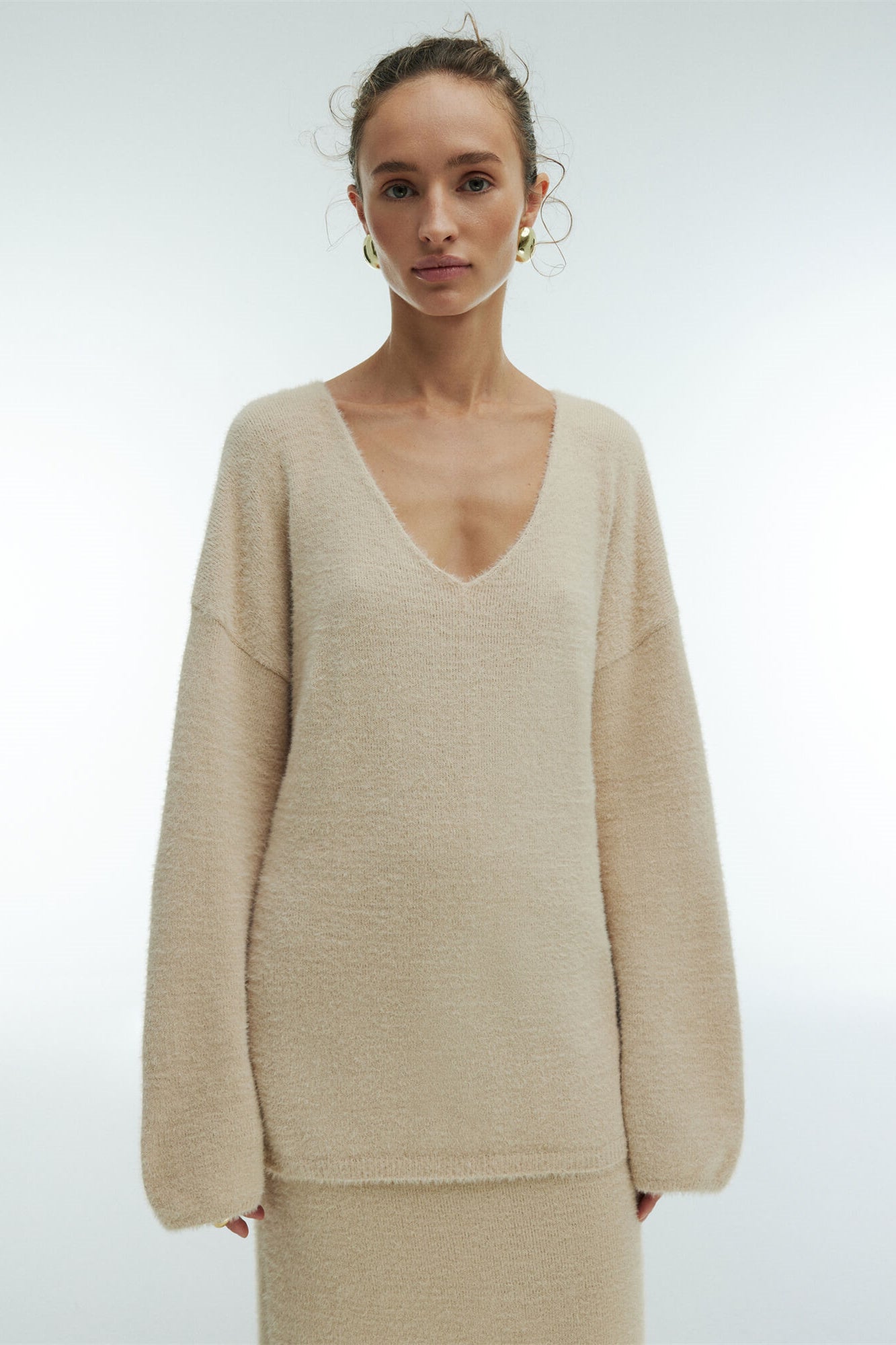 Woman in off-white boucle knit sweater and maxi skirt set with fuzzy slippers