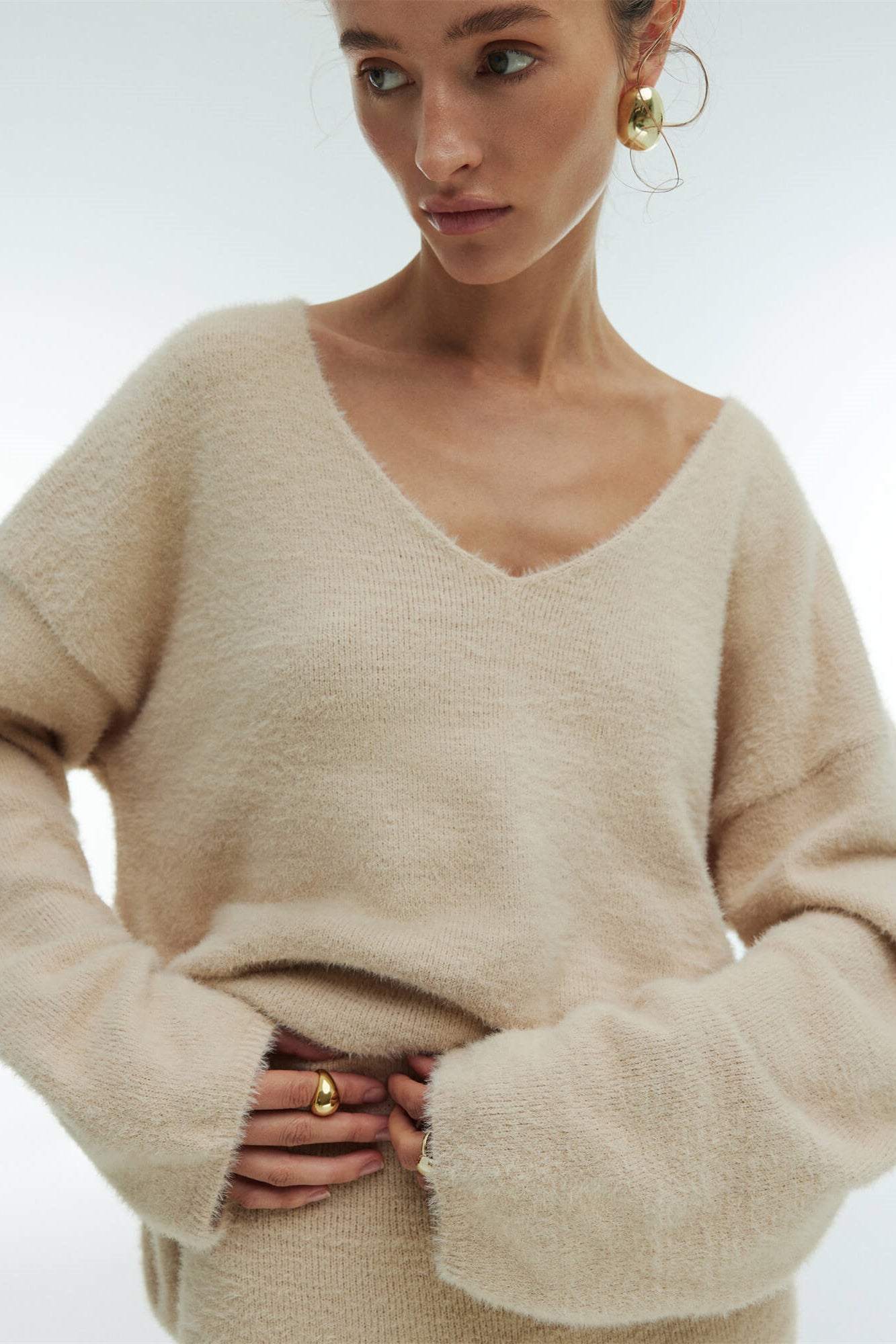 Woman in off-white boucle knit sweater and maxi skirt set with fuzzy slippers