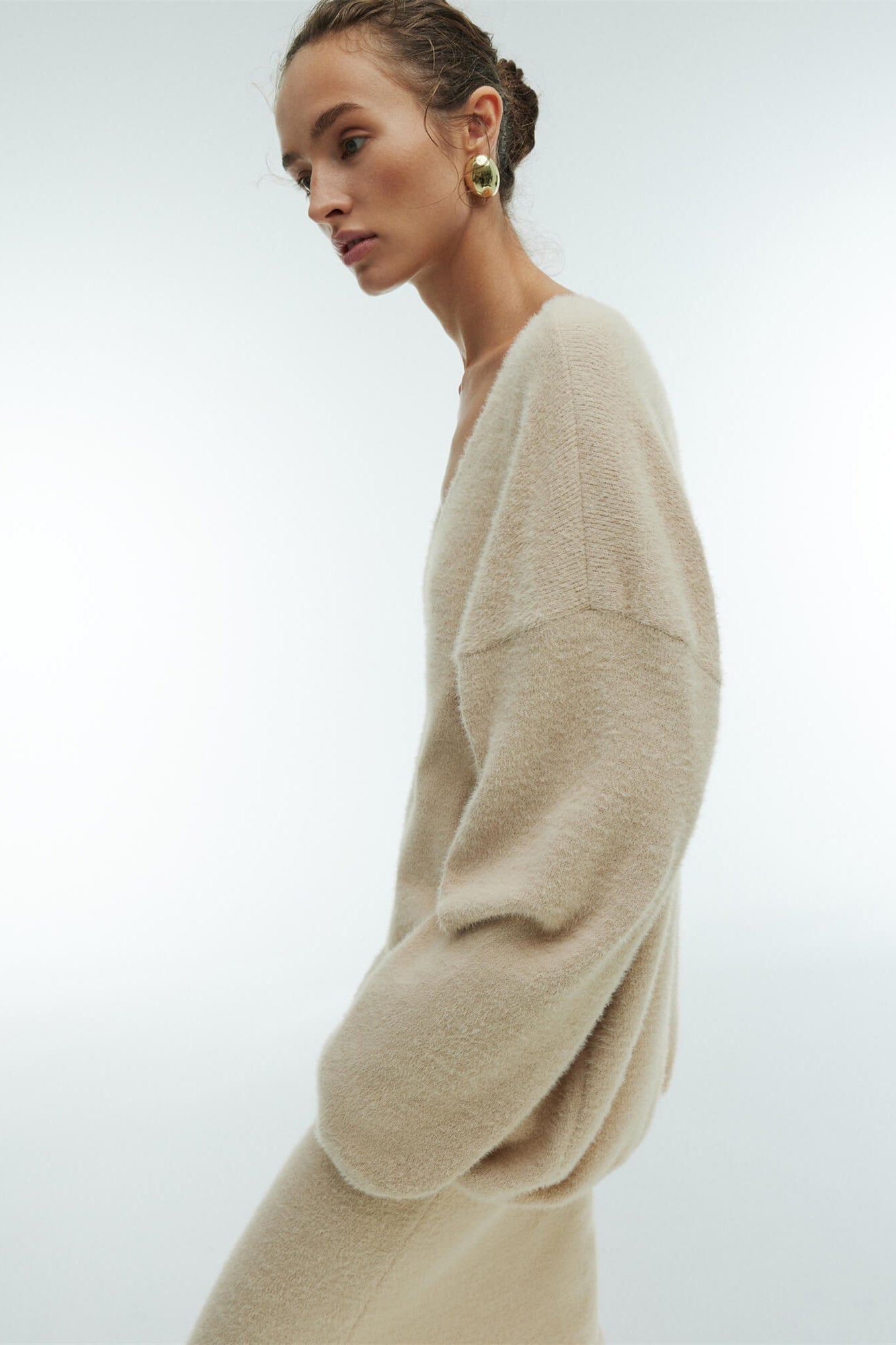 Woman in off-white boucle knit sweater and maxi skirt set with fuzzy slippers