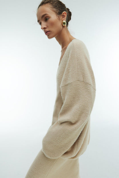 Woman in off-white boucle knit sweater and maxi skirt set with fuzzy slippers