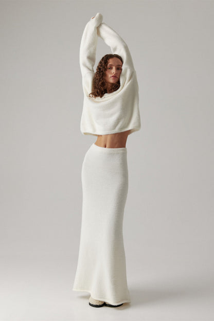 Woman in off-white boucle knit sweater and maxi skirt set with fuzzy slippers