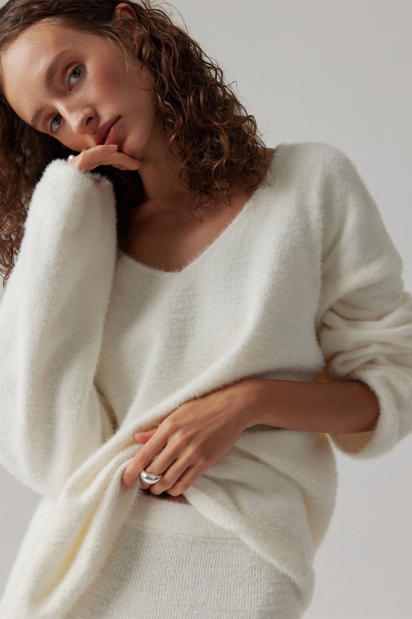 Woman in off-white boucle knit sweater and maxi skirt set with fuzzy slippers