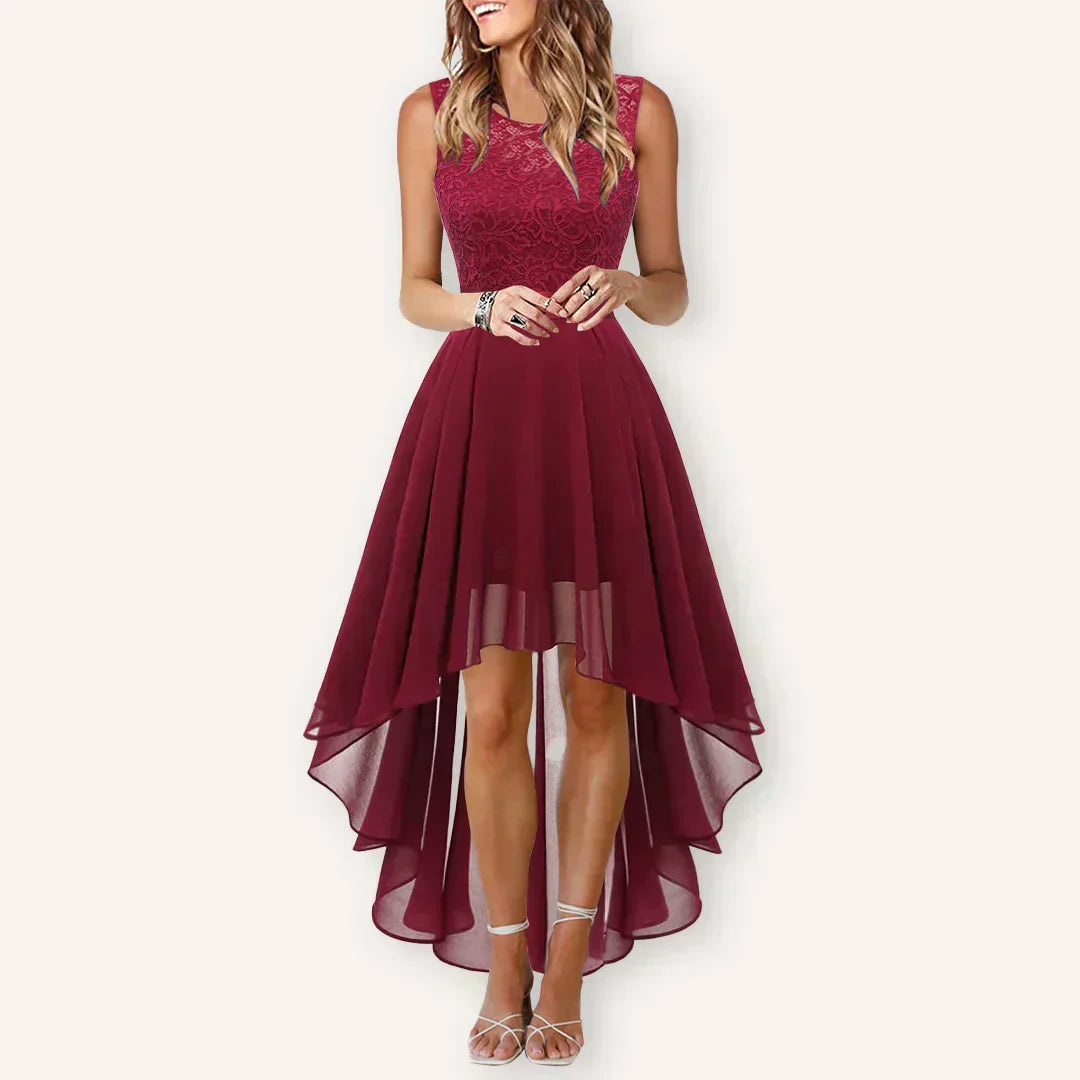 Deep Red - A woman wearing a sleeveless burgundy high-low dress with a textured lace bodice and a flowing chiffon skirt, paired with silver strappy heels.