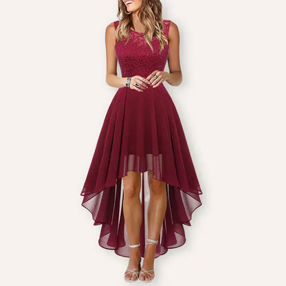 Deep Red - A woman wearing a sleeveless burgundy high-low dress with a textured lace bodice and a flowing chiffon skirt, paired with silver strappy heels.