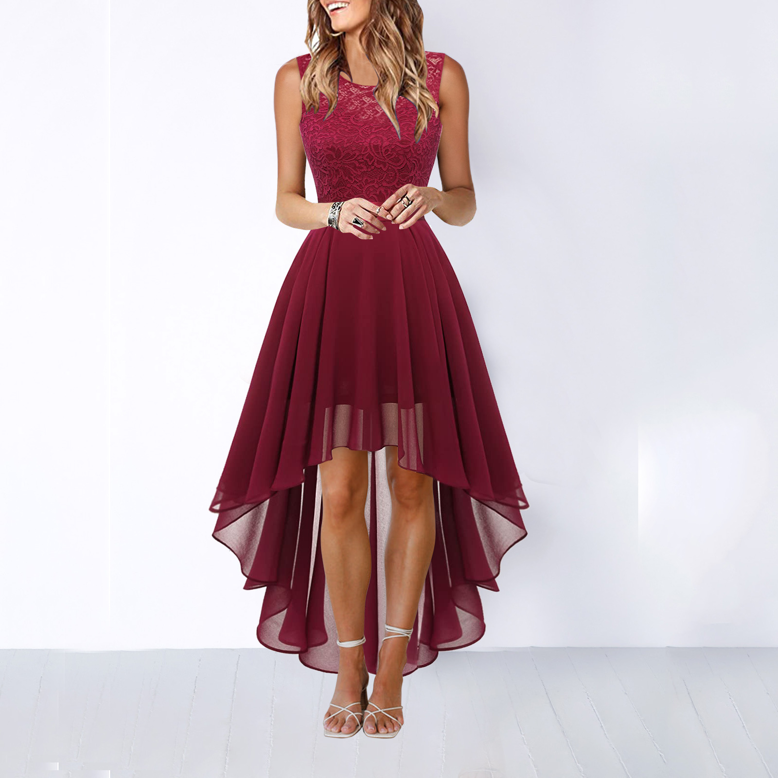Deep Red - A woman wearing a sleeveless burgundy high-low dress with a textured lace bodice and a flowing chiffon skirt, paired with silver strappy heels.