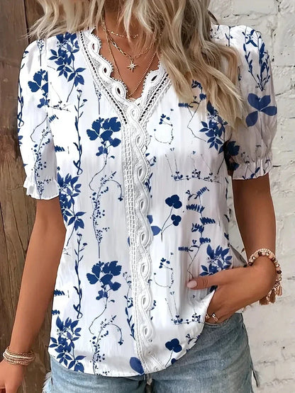 Dark Blue - A woman wearing a light blue and white striped blouse with a blue botanical leaf print, featuring a white lace-trimmed V-neckline and short puff sleeves.