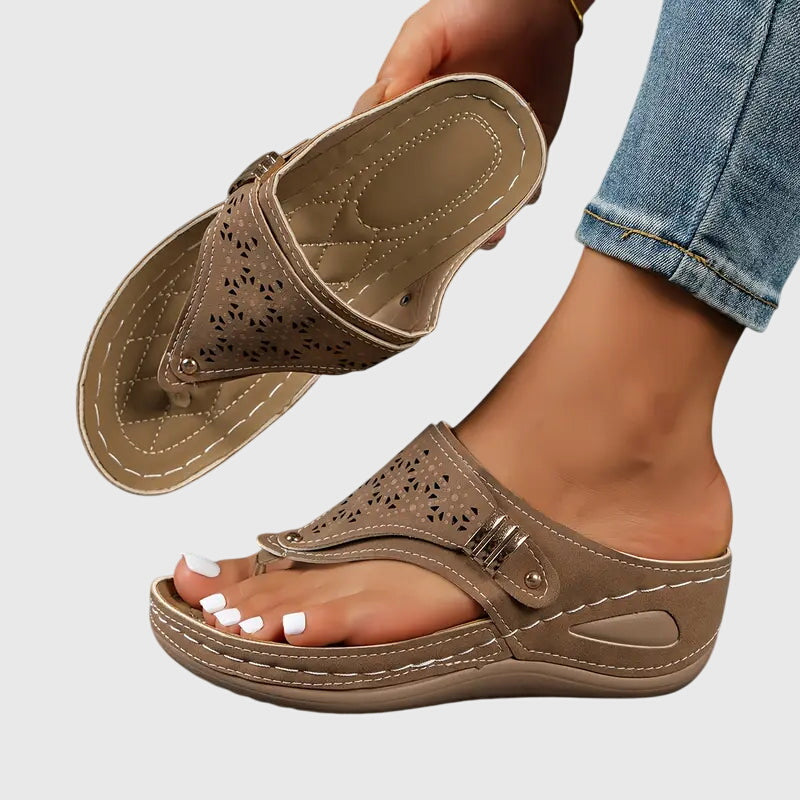 Brown - Faux-leather wedge sandals featuring laser-cut upper detailing, a decorative side buckle, contoured stitched footbed, and contrast stitching along the sole