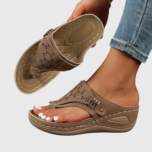 Brown - Faux-leather wedge sandals featuring laser-cut upper detailing, a decorative side buckle, contoured stitched footbed, and contrast stitching along the sole