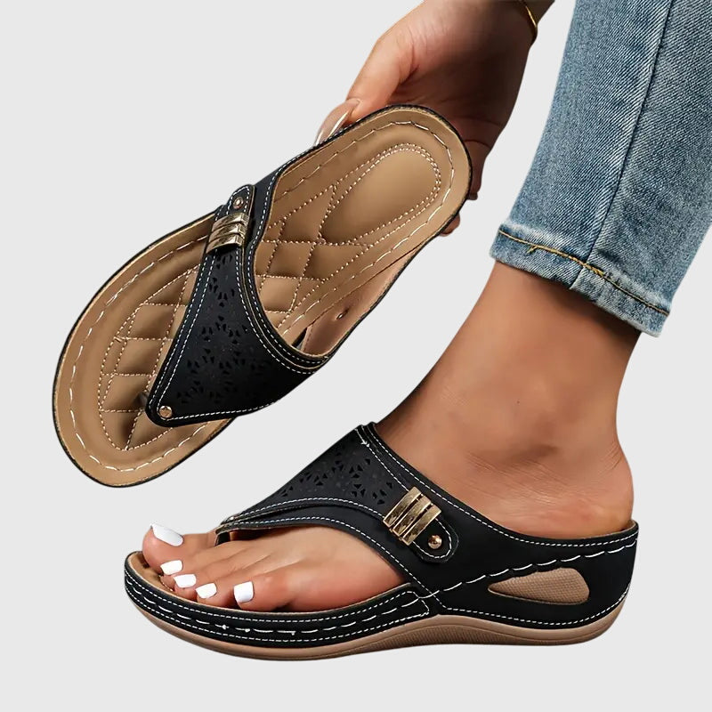 Black - Faux-leather wedge sandals featuring laser-cut upper detailing, a decorative side buckle, contoured stitched footbed, and contrast stitching along the sole