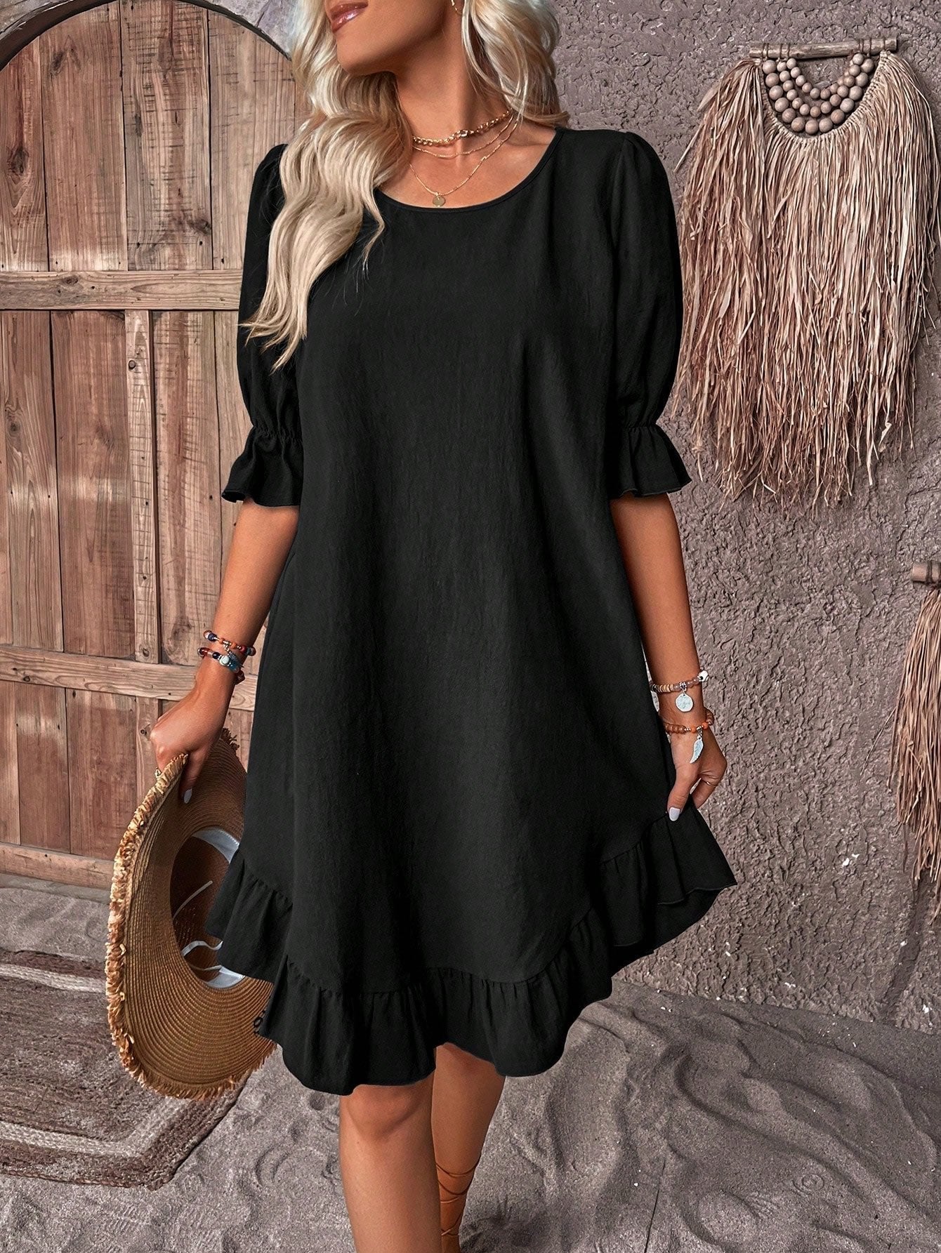 Black - A woman wearing a navy blue linen-blend sundress with puff sleeves, ruffle cuffs, and a flounce hem, holding a straw hat.