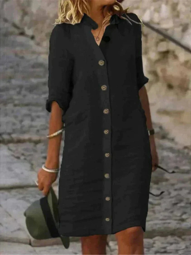 Black - Woman walking outdoors wearing a long-sleeve, button-front linen midi dress with a collar, holding a hat.