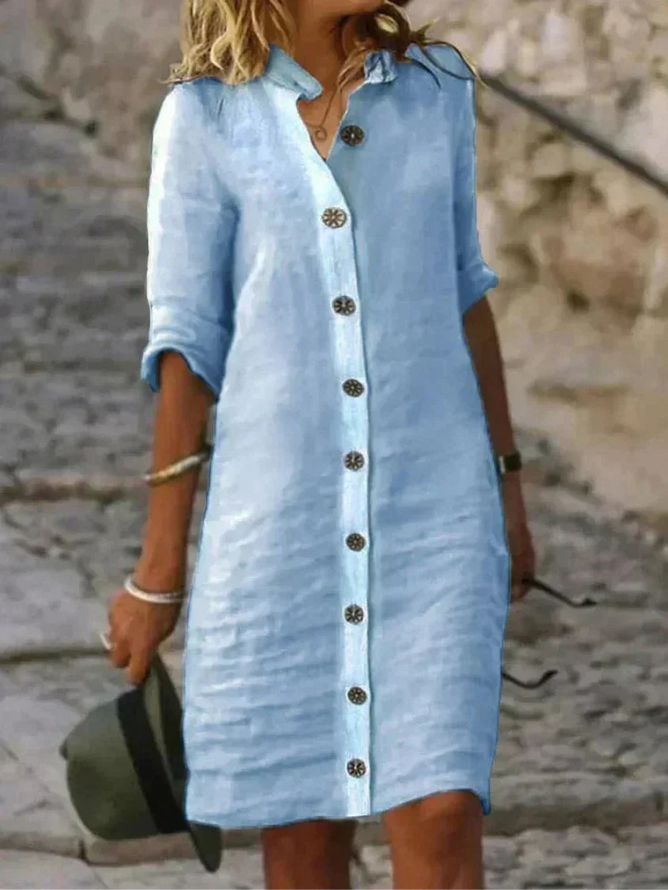 Light Blue - Woman walking outdoors wearing a long-sleeve, button-front linen midi dress with a collar, holding a hat.