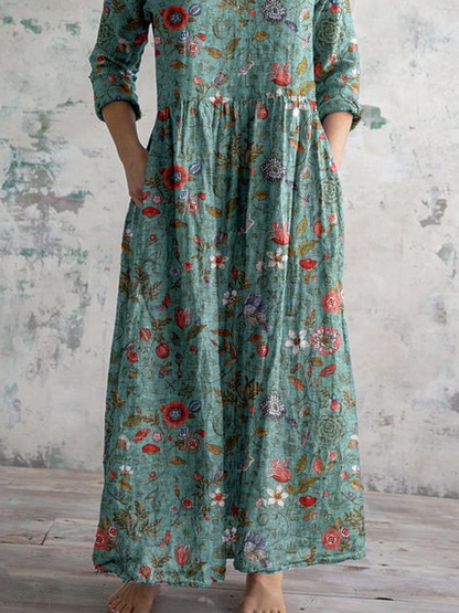 3XL - Woman wearing a long, textured floral maxi dress with 3/4 sleeves and hands resting in side pockets