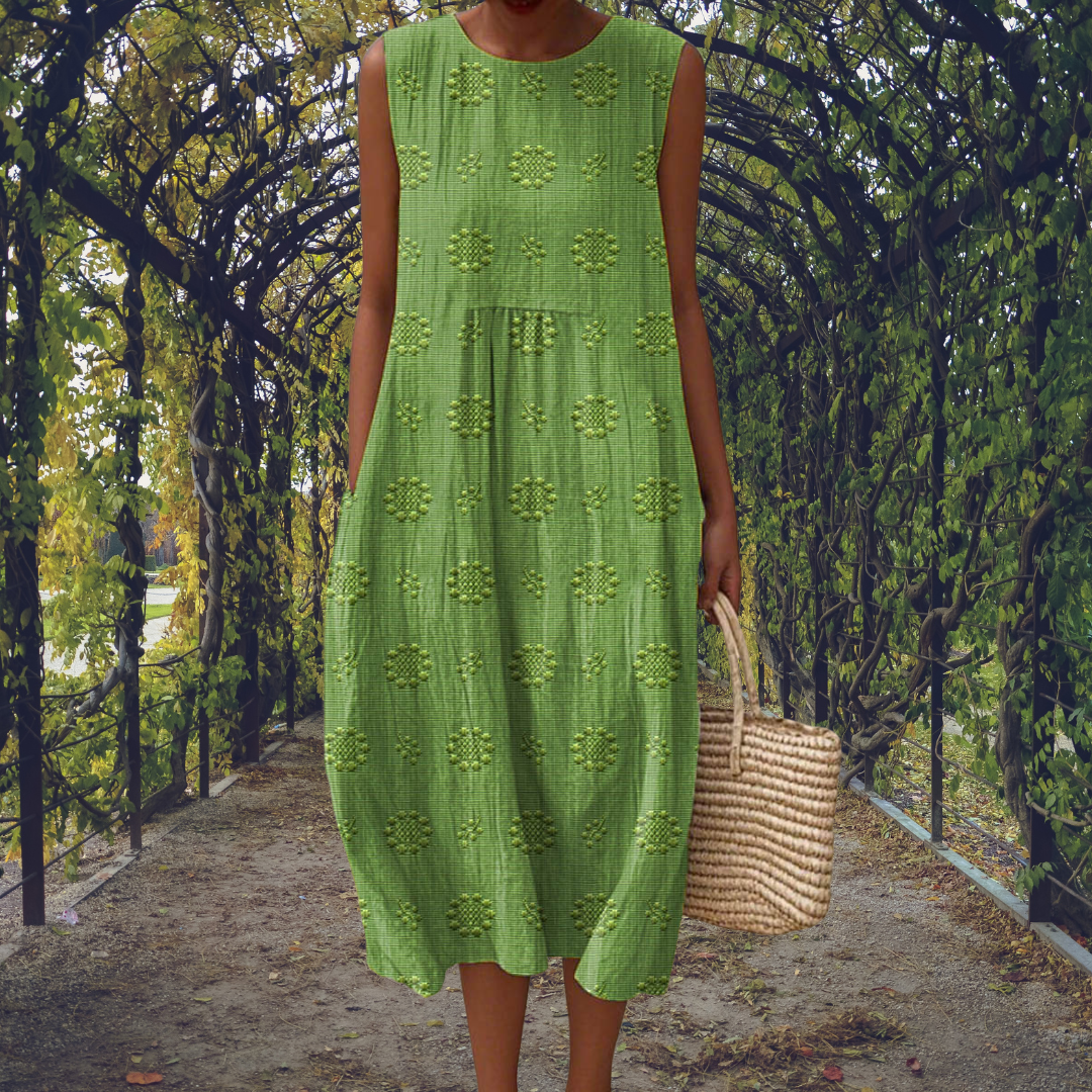 Green - Woman wearing a sleeveless, A-line midi sundress featuring an all-over 3D floral applique pattern and side seam pockets, standing on a gravel path.