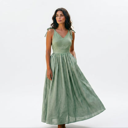 Green - Model wearing a solid woven maxi dress featuring tie-shoulder straps, a fitted waist, and a full sweeping skirt against a white studio background.