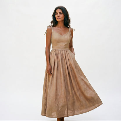 Khaki - Model wearing a solid woven maxi dress featuring tie-shoulder straps, a fitted waist, and a full sweeping skirt against a white studio background.