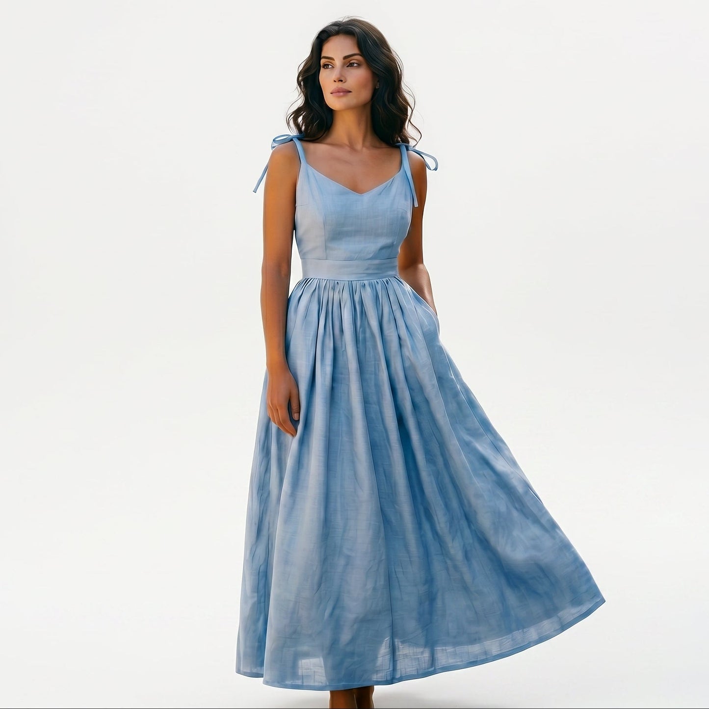 Sky Blue - Model wearing a solid woven maxi dress featuring tie-shoulder straps, a fitted waist, and a full sweeping skirt against a white studio background.