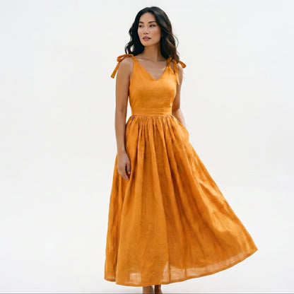 Orange - Model wearing a solid woven maxi dress featuring tie-shoulder straps, a fitted waist, and a full sweeping skirt against a white studio background.