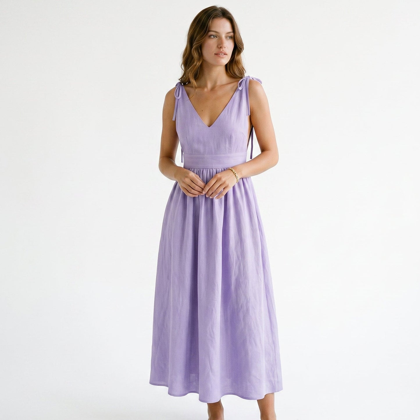 Lavender - Model wearing a solid woven maxi dress featuring tie-shoulder straps, a fitted waist, and a full sweeping skirt against a white studio background.