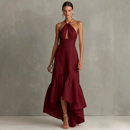 Wine Red - A woman wearing a black linen-blend halter neck maxi dress with a front keyhole cutout, a fitted waist, and a dramatic ruffled high-low hemline.