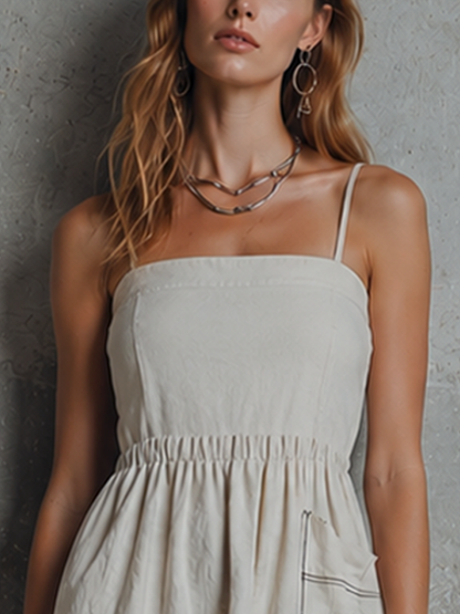 Off-White - Woman wearing a woven mini dress with spaghetti straps, a gathered elastic waist, and a front patch pocket with contrast stitching, holding a fabric bag.