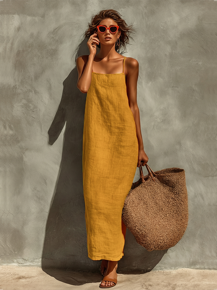 Yellow - Woman wearing a textured, relaxed-fit spaghetti strap maxi dress, holding a large woven tote bag against a concrete wall.