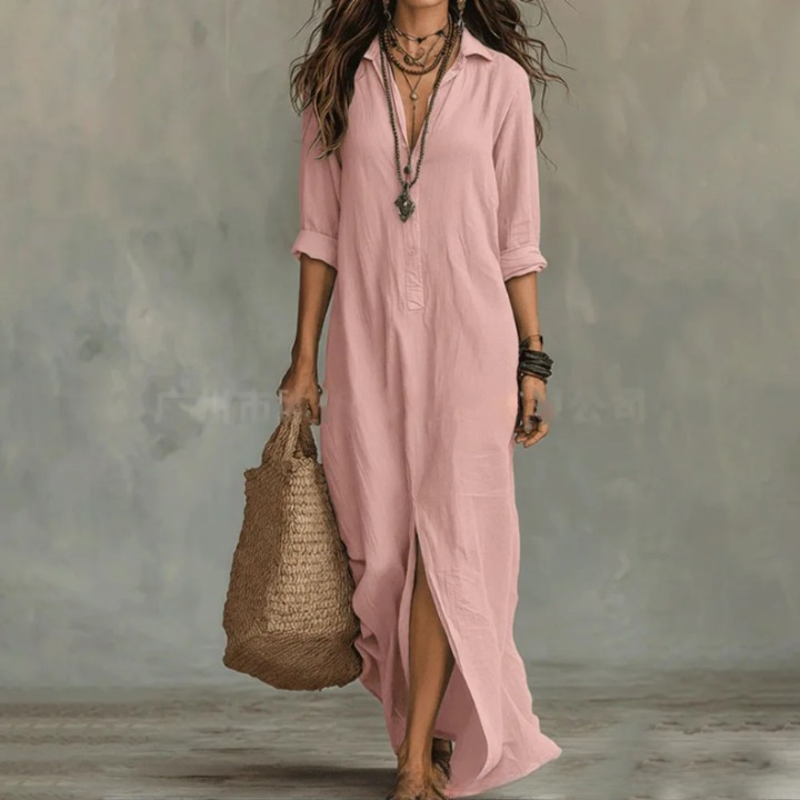 Pink - A woman wearing a relaxed-fit white linen maxi sundress with a collared V-neck, rolled sleeves, and a front slit, carrying a woven straw tote bag.