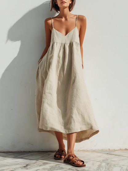 Beige - Model wearing an oversized woven maxi dress with spaghetti straps, a V-neckline, and side pockets, standing outdoors in bright sunlight.