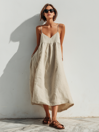 Beige - Model wearing an oversized woven maxi dress with spaghetti straps, a V-neckline, and side pockets, standing outdoors in bright sunlight.