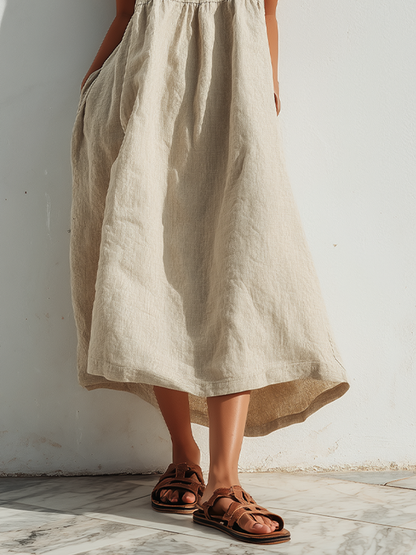 Beige - Model wearing an oversized woven maxi dress with spaghetti straps, a V-neckline, and side pockets, standing outdoors in bright sunlight.