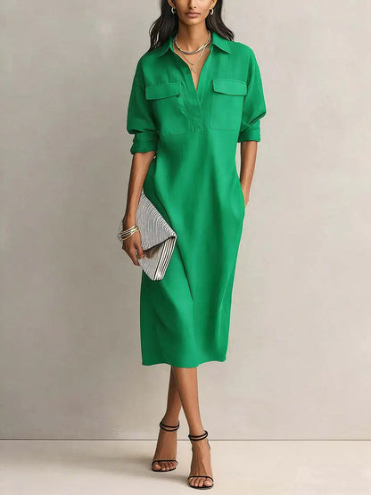 Green - A woman wearing a light blue linen midi shirt dress with a collar, V-neckline, chest flap pockets, and half sleeves, styled with black strappy heels and a striped clutch.
