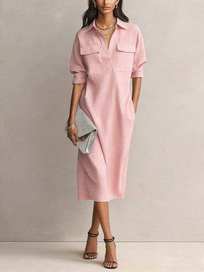 Pink - A woman wearing a light blue linen midi shirt dress with a collar, V-neckline, chest flap pockets, and half sleeves, styled with black strappy heels and a striped clutch.