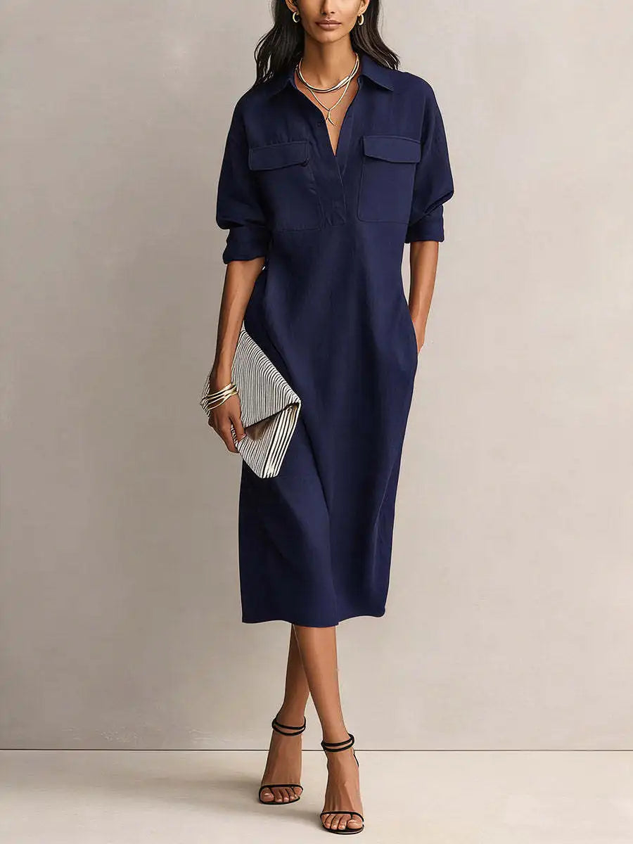 Navy Blue - A woman wearing a light blue linen midi shirt dress with a collar, V-neckline, chest flap pockets, and half sleeves, styled with black strappy heels and a striped clutch.