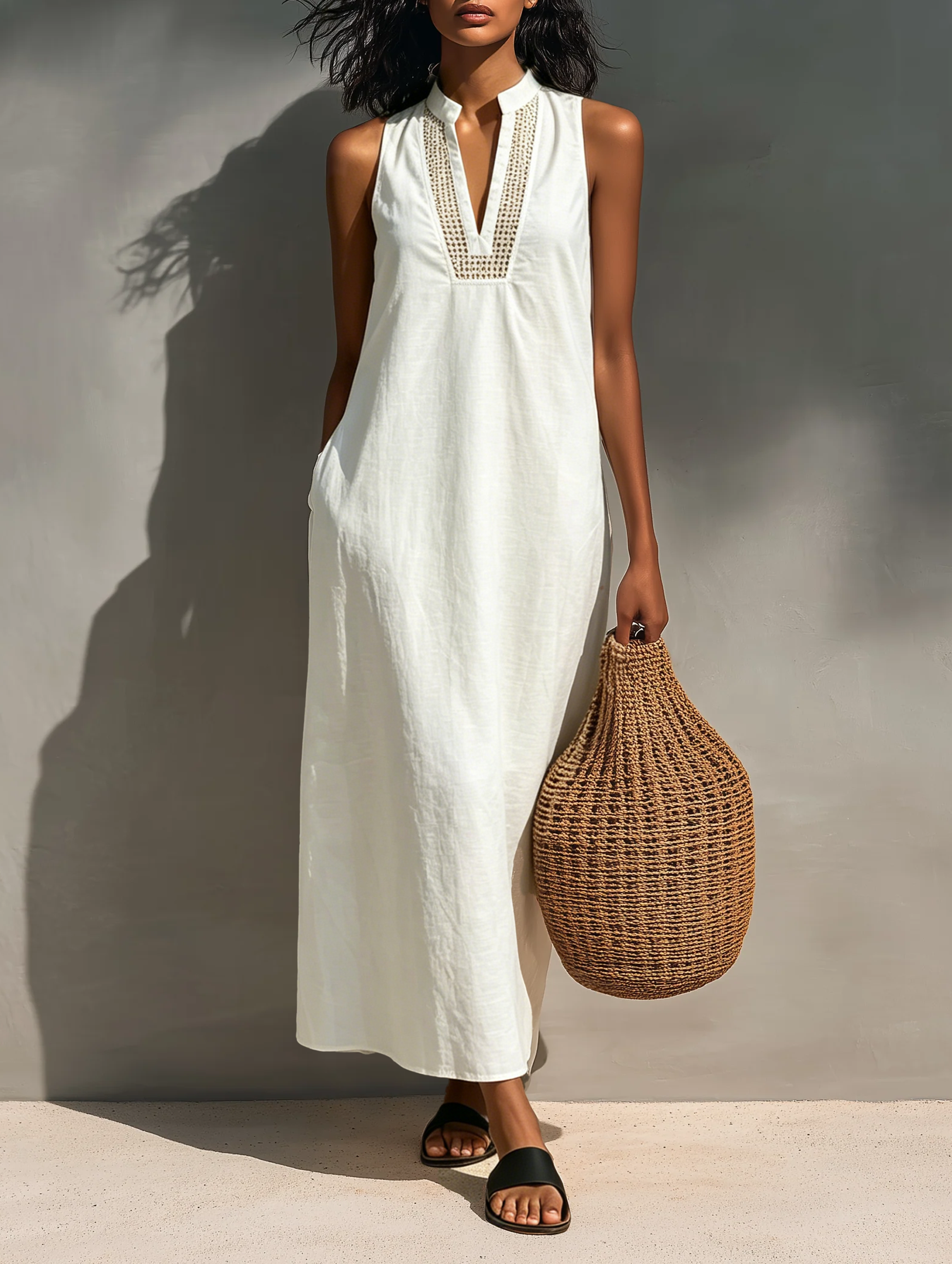 Woman modeling a sleeveless relaxed maxi dress featuring a textured V-neckline and fluid drape, carrying a large woven basket bag.