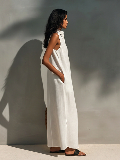 Woman modeling a sleeveless relaxed maxi dress featuring a textured V-neckline and fluid drape, carrying a large woven basket bag.