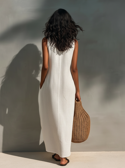 Woman modeling a sleeveless relaxed maxi dress featuring a textured V-neckline and fluid drape, carrying a large woven basket bag.