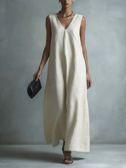White - Woman wearing a sleeveless, light-colored linen V-neck maxi dress with a relaxed A-line silhouette, holding a small black clutch.