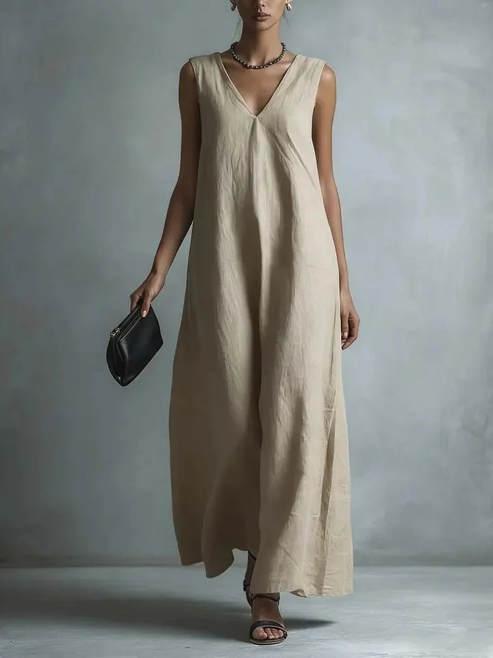 Khaki - Woman wearing a sleeveless, light-colored linen V-neck maxi dress with a relaxed A-line silhouette, holding a small black clutch.