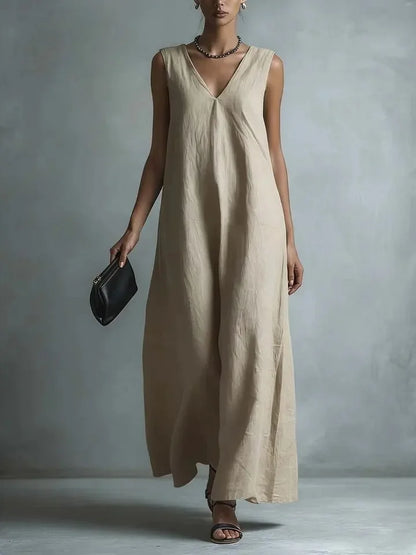 Khaki - Woman wearing a sleeveless, light-colored linen V-neck maxi dress with a relaxed A-line silhouette, holding a small black clutch.