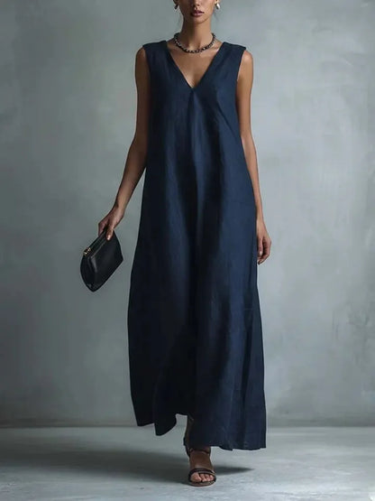 Blue - Woman wearing a sleeveless, light-colored linen V-neck maxi dress with a relaxed A-line silhouette, holding a small black clutch.