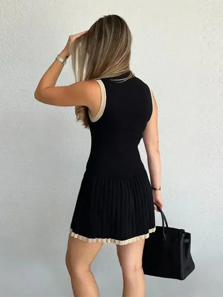 Woman in black ribbed knit mini dress with tan trim, holding coffee and purse.