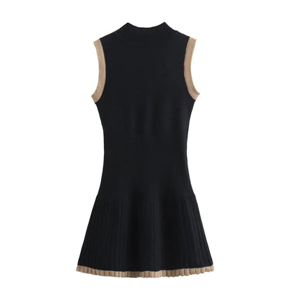 Woman in black ribbed knit mini dress with tan trim, holding coffee and purse.