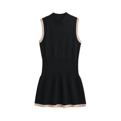 Woman in black ribbed knit mini dress with tan trim, holding coffee and purse.