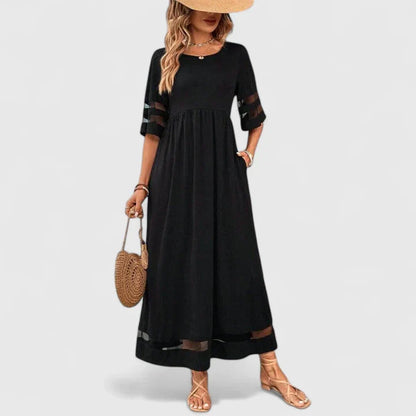 Red - A woman wearing a burgundy maxi dress with elbow-length sleeves and a scoop neckline, featuring sheer mesh stripe inserts on the sleeves and hem, styled with a straw hat and bag.