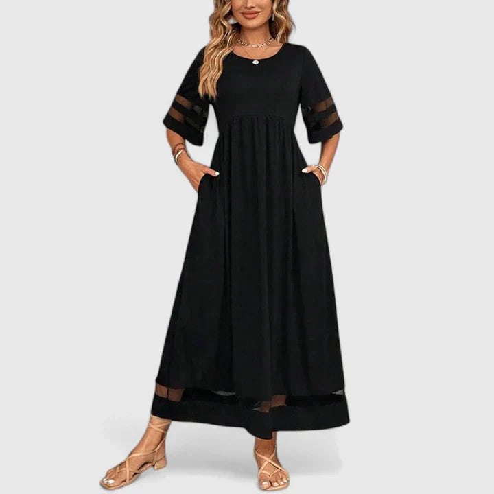 Red - A woman wearing a burgundy maxi dress with elbow-length sleeves and a scoop neckline, featuring sheer mesh stripe inserts on the sleeves and hem, styled with a straw hat and bag.