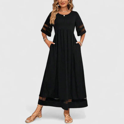 Red - A woman wearing a burgundy maxi dress with elbow-length sleeves and a scoop neckline, featuring sheer mesh stripe inserts on the sleeves and hem, styled with a straw hat and bag.
