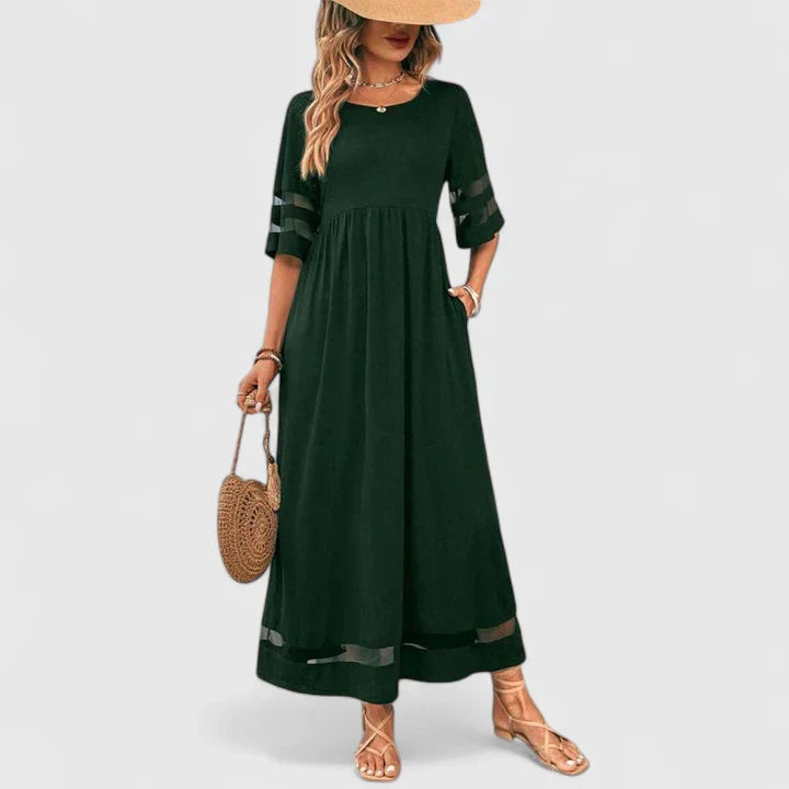 Green - A woman wearing a burgundy maxi dress with elbow-length sleeves and a scoop neckline, featuring sheer mesh stripe inserts on the sleeves and hem, styled with a straw hat and bag.