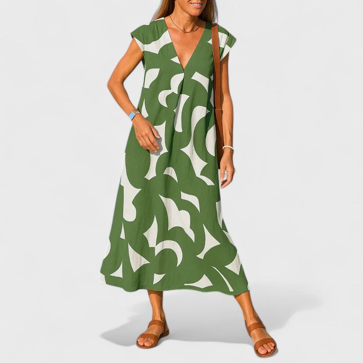Green - A woman wearing a black and white abstract graphic print midi dress with a V-neckline, cap sleeves, and a relaxed shift silhouette, styled with brown leather sandals and a shoulder bag.