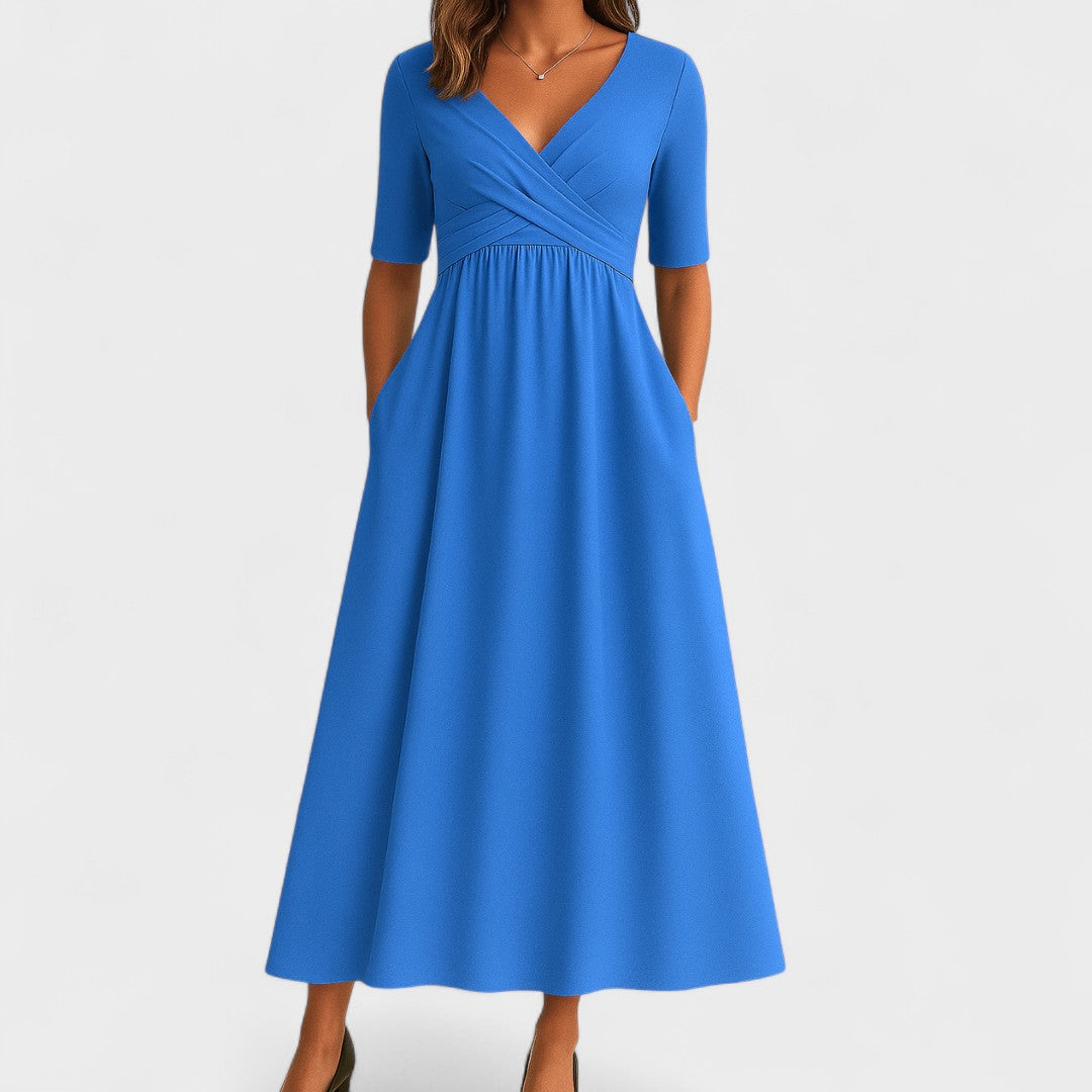 Light blue - A woman wearing a heather gray jersey knit midi dress featuring a surplice V-neckline, ruched wrap bodice, short sleeves, and a flowy A-line skirt with side pockets.